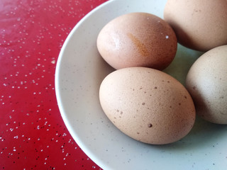 Four boiled eggs are placed on white plates. Placed on a red table.