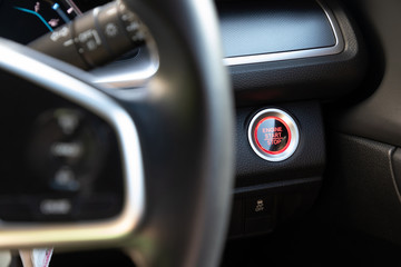 engine start button on black interior leather. push start system. wheel steering is foreground.
