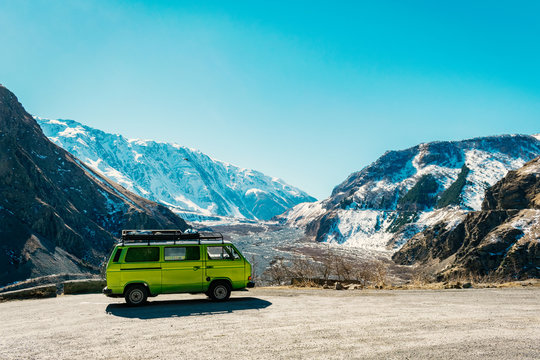 Vintage classic van parked beside the road among the high Caucasus peaks on the far north of Georgia. Breath taking view.