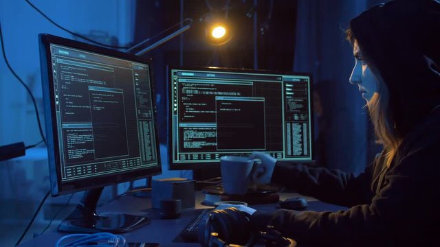 cybercrime, hacking and technology concept - female hacker in dark room creating code or using computer virus program for cyber attack