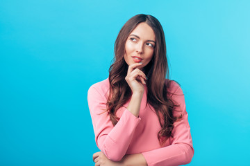 Portrait of thoughtful wondering woman looking sideways isolated over blue background