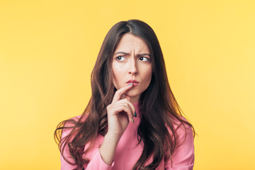 Thoughtful confused woman looking away isolated over yellow background