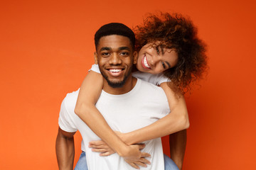 Cute couple in love embracing on orange background