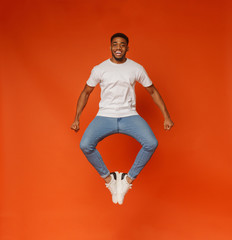 Positive african american guy jumping and clapping his legs