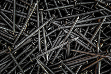 Detailed dark background and texture full frame of pile metal steel nails for construction of a carpenter.