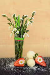 Romantic composition - spring flowers with homemade coconut balls and strawberries decorated with daisy flowers