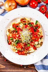 Pasta with tomato sauce and vegetables on wooden table