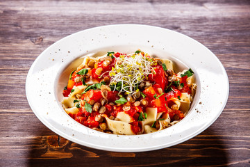 Pasta with tomato sauce and vegetables on wooden table