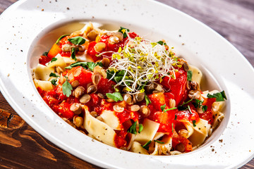Pasta with tomato sauce and vegetables on wooden table