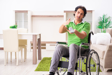 Young handsome man in wheelchair at home