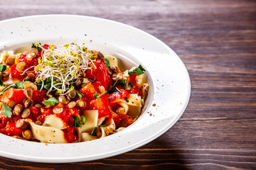 Pasta with tomato sauce and vegetables on wooden table