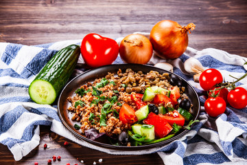 Groats with lentils and vegetables on wooden table