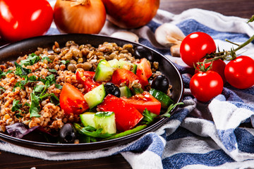 Groats with lentils and vegetables on wooden table