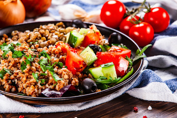 Groats with lentils and vegetables on wooden table