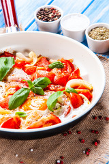 Shakshuka - fried eggs with vegetables in frying pan