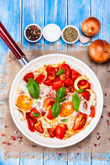 Shakshuka - fried eggs with vegetables in frying pan
