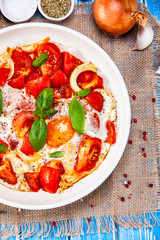 Shakshuka - fried eggs with vegetables in frying pan