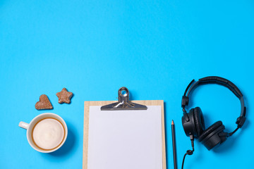 Music or podcast background with headphones, microphone, coffee and blank on blue table, flat lay....