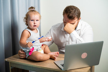 Freelancer work concept. tired dad working at home with a laptop, holding the baby in his arms