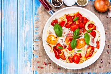 Shakshuka - fried eggs with vegetables in frying pan