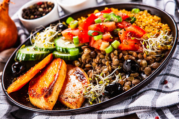 Groats with lentils and vegetables on wooden table
