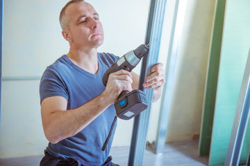 male builder installs metal ceiling profile