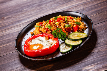 Fried egg, groats and vegetables on wooden table