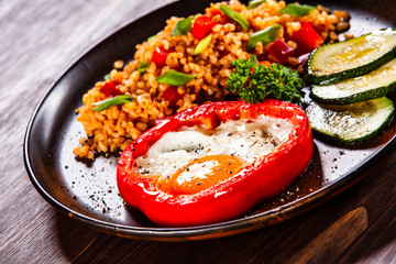 Fried egg, groats and vegetables on wooden table