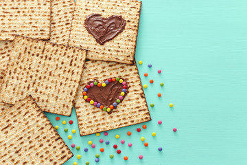 Pesah celebration concept (jewish Passover holiday) with chocolate heart and colorful candies over matzah. Top view flat lay