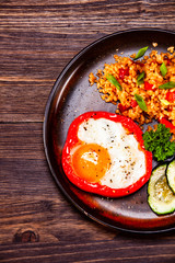 Fried egg, groats and vegetables on wooden table