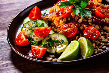 Groats with lentils and vegetables on wooden table