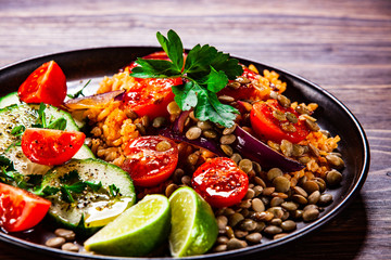 Groats with lentils and vegetables on wooden table