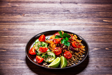 Groats with lentils and vegetables on wooden table