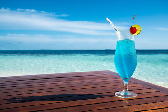 Blue lagoon cocktail on table and beautiful sea background