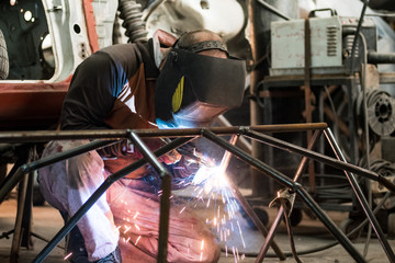 Workers in the mask are welding steel in workshop
