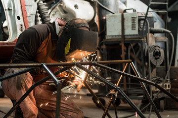 Fototapeta na wymiar Workers in the mask are welding steel in workshop