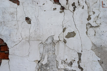 Macro texture of peeled paint on a white concrete wall.