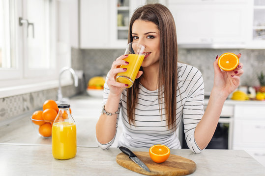 Close up Attractive Sensual Bare Woman drinking juice while Holding Sliced Orange Fruit.