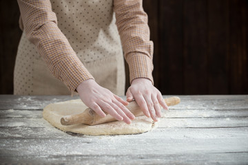  hands cooking dough on dark wooden background