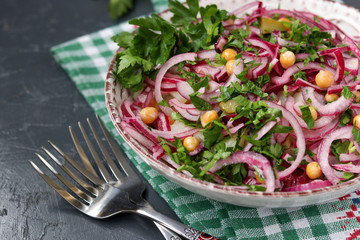 Healthy salad with chickpeas, potatoes, red onions and pickled cucumbers in a plate