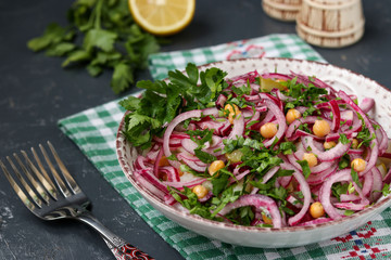 Healthy salad with chickpeas, potatoes, red onions and pickled cucumbers in a plate
