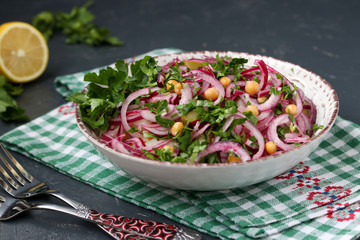Healthy salad with chickpeas, potatoes, red onions and pickled cucumbers in a plate
