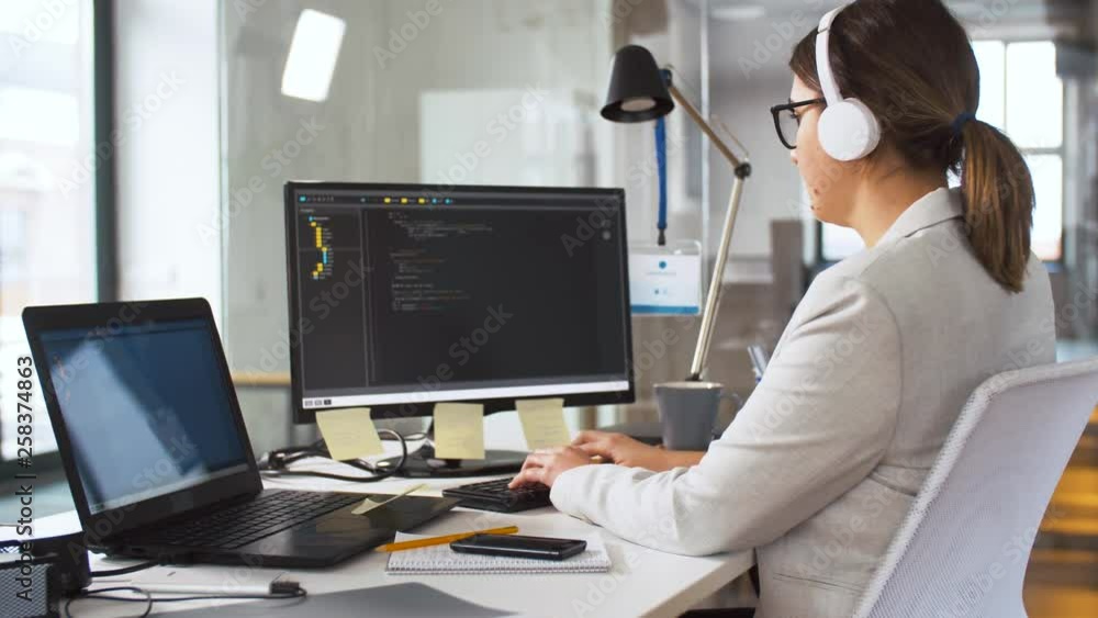 Poster business, programming and technology concept - female programmer in headphones working with script o