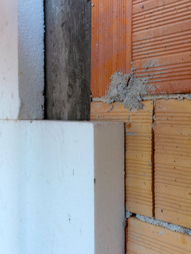 worker mounts sheets of polystyrene on external vertical walls