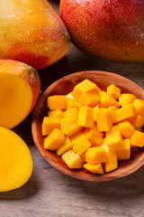 Mango fruit and mango cubes on the wooden table.