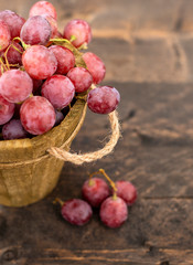 Rose grapes in wooden bucket on a woden table