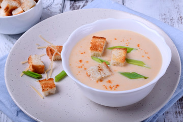 Cream soup with croutons, green onion and cheese in a white bowl