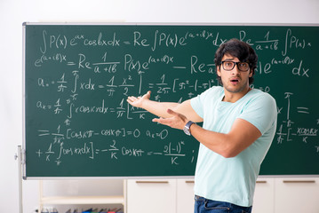 Young male student mathematician in front of chalkboard
