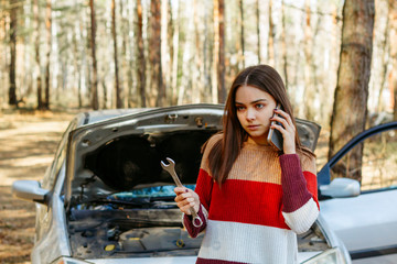 the girl at the broken car is on the phone