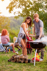 Girl and boy preparing barbecue - obrazy, fototapety, plakaty